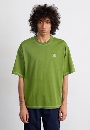 Grön bomullströja med rund hals, korta ärmar och vit sömnad. Har en liten vit adidas-logotyp på vänster bröst.