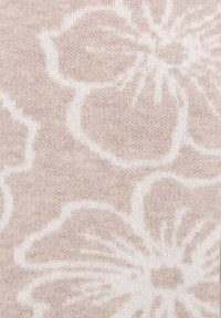 Lichtbeige stof met een bloemenpatroon in het wit. De textuur is zacht en gebreid, met duidelijke bloemvormen en -omtrekken.