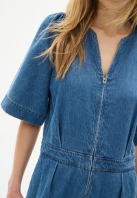 Denim-Overall mit Reißverschluss vorne, kurzen Ärmeln und tailliertem Bund. Verfügt über einen klassischen blauen Farbton und dezente Nähte.
