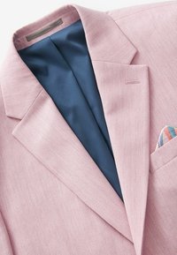 Hellrosa Blazer aus einem strukturierten Stoff. Innen ist er mit einem glatten dunkelblauen Futter versehen und hat ein Einstecktuch mit geometrischen Mustern in Pastellfarben.