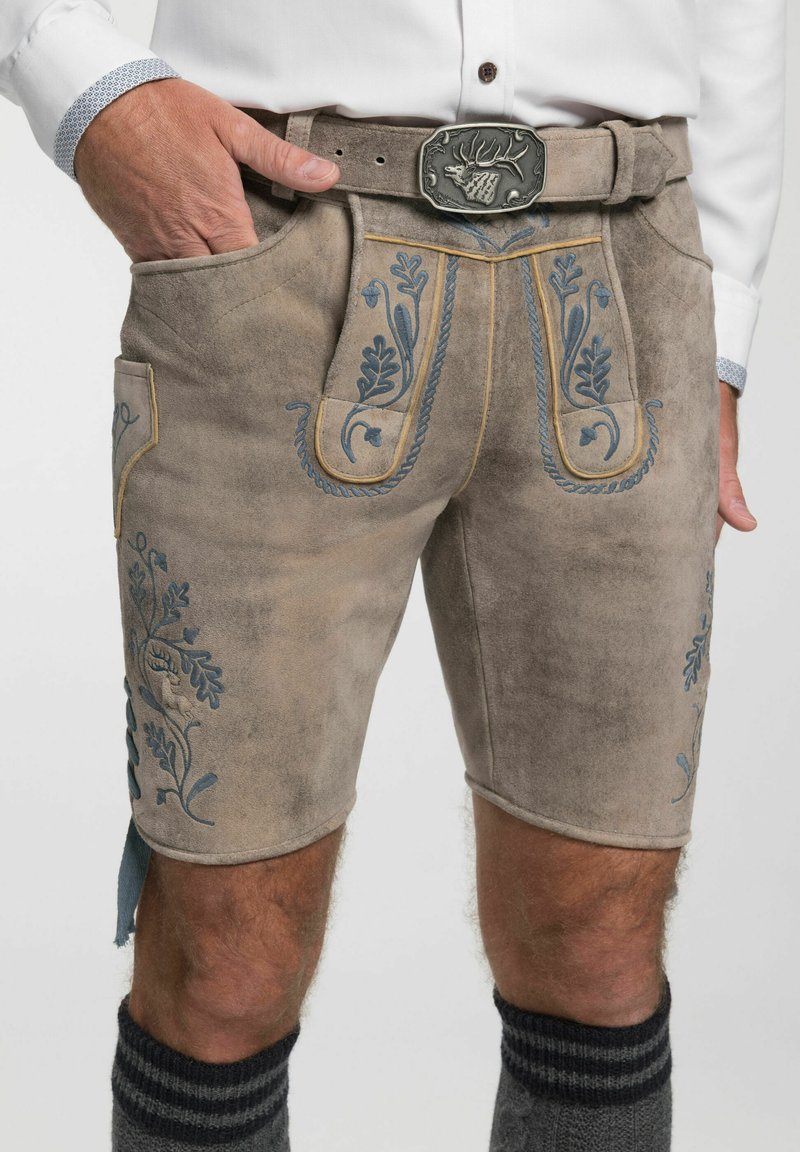 Helle braune Wildleder-Shorts mit kunstvoller blauer Blumenstickerei, Gürtelschlaufen, Taschen und einer dekorativen silbernen Schnalle. Graue, knielange Socken.
