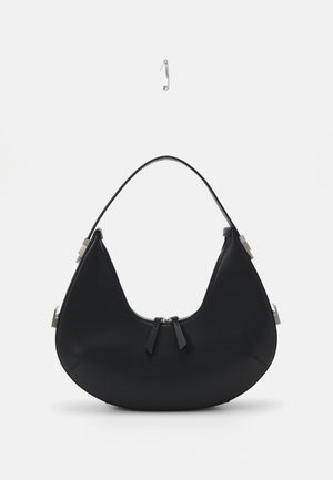Bolsa de mão preta em couro com forma curva, fecho com zíper, dois borlas pretas e detalhes em metal prateado, incluindo um detalhe de ligação único.