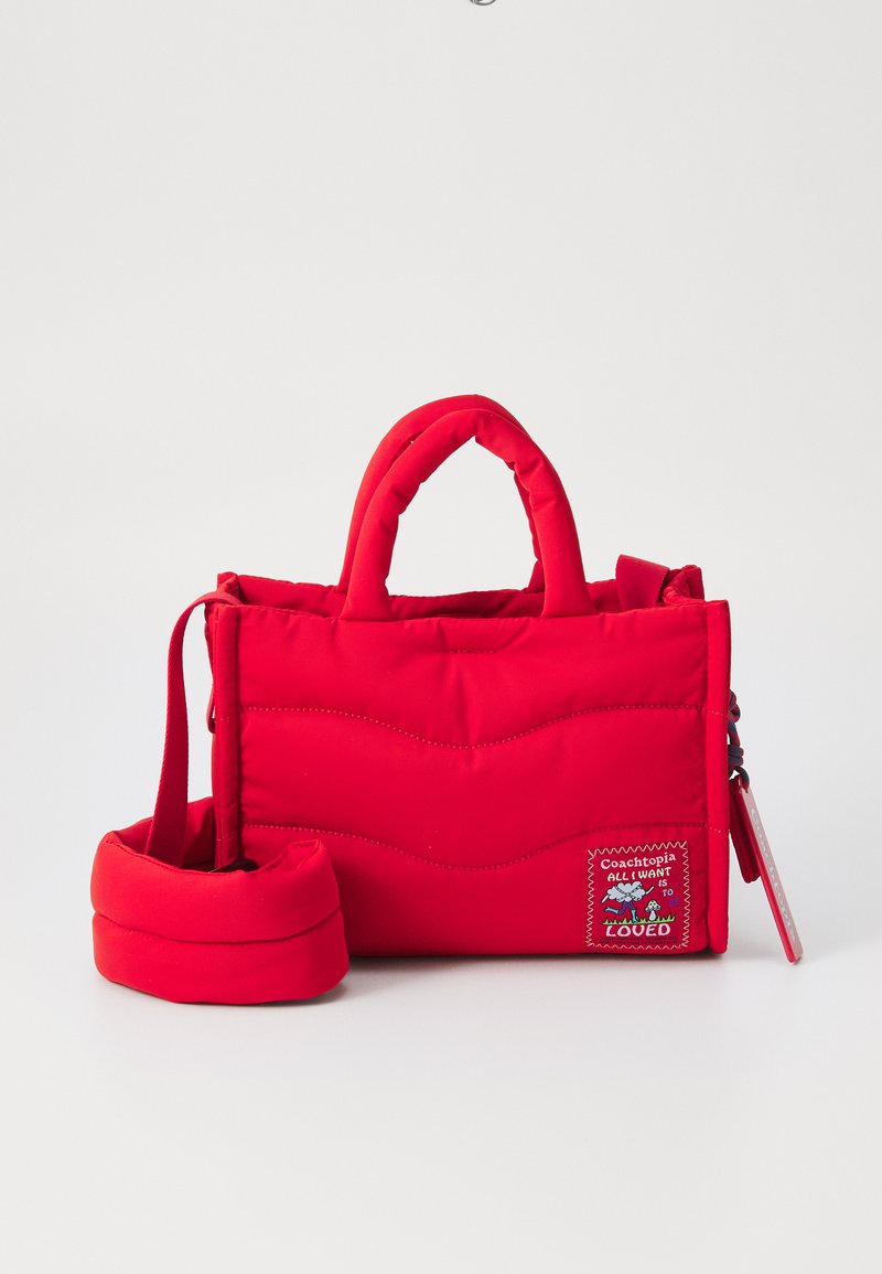Sac à main rembourré rouge avec poignées courtes, bandoulière amovible et un patch décoratif avec texte et graphiques. Surface texturée et couture en zigzag.