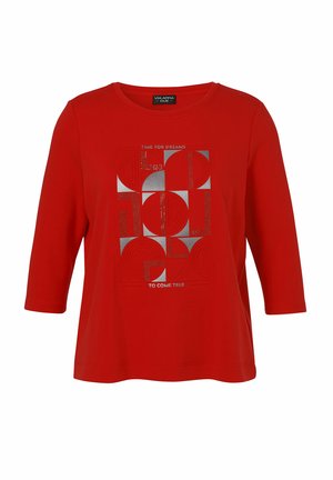 Rotes Shirt mit Dreiviertelärmeln, verziert mit abstrakten silbernen geometrischen Formen und dem Text "TIME FOR DREAMS TO COME TRUE" auf der Vorderseite.