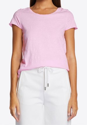 Jasnoróżowa koszulka z krótkim rękawem i okrągłym dekoltem, wykonana z fakturowanej tkaniny. Połączona z białymi spodniami z szerokimi nogawkami, wyposażonymi w sznurek.
