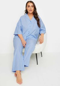 Blå och vit randig pyjamas set med en kragbomullsskjorta med korta ärmar och löst sittande byxor, med en avslappnad design och mjukt tyg.