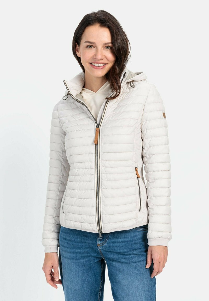 Letvægtig, off-white jakke med quiltet design, lynlås foran, justerbar hætte og tan læderdetaljer. Kombineret med blå jeans.
