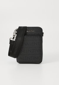 Sac bandoulière noir en tissu à surface texturée, avec logo en relief et une sangle amovible. Fermeture zippée et design minimaliste.