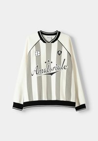 Sudadera crema con rayas verticales negras, cuello y puños acanalados, y texto gráfico "Amatoriale" en la parte frontal. Detalle de acentos de logo.