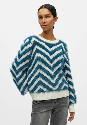 Fuzzy sweater med et blåt og hvidt zigzag-mønster, ribbede manchetter og kant, med en tekstureret, plyss finish.