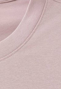 Light pink cotton fabric features a smooth texture with a round neckline and fine ribbed detailing along the edge.