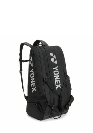 Zwarte Yonex sportrugzak met meerdere afsluitbare vakken en verstelbare schouderbanden, schuine aanzicht op een witte achtergrond.