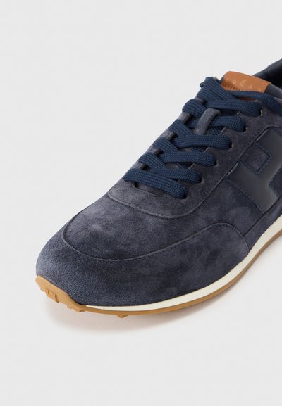 Αθλητικό παπούτσι από σουέντ σε ναυτικό μπλε με υφή, διαθέτει ελαστική σόλα, δέσιμο με κορδόνια και αντίθετο λογότυπο στο πλάι.