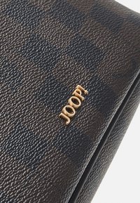 Brown textured material wallet featuring a gold logo, with a checkered pattern and a smooth zipper edge.