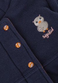 Giacca in pile navy con un design di gufo ricamato, bottoni arancioni con motivi a foglia e un finish in tessuto morbido e testurizzato.