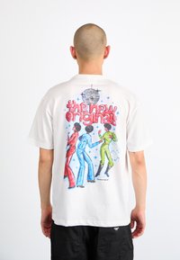 White t-shirt featuring a colorful graphic on the back with three dancing figures in red, blue, and green. Text above reads "the new originals."