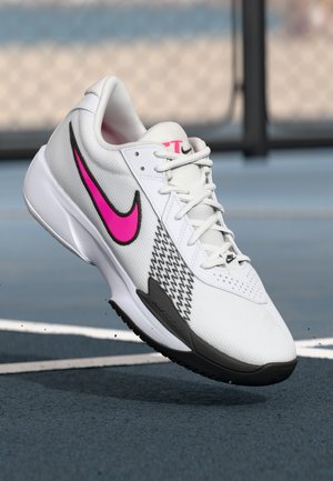 Chaussure de sport blanche avec un dessus en maille texturée, des accents noirs et roses, un motif pied-de-poule sur le côté et une semelle en caoutchouc.