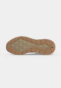 Σόλα ενός καφέ παπουτσιού Timberland με μοτίβο πέλματος, που περιλαμβάνει σταυρωτά μεγάλα δοντάκια και ένα μικρό πράσινο εξάγωνο κοντά στη φτέρνα.