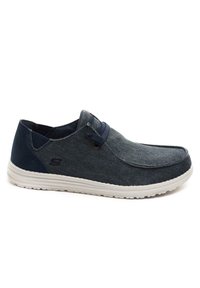 Calzature slip-on in denim blu scuro con dettagli in blu navy. Presenta una punta rotonda e una suola in gomma bianca per comfort e flessibilità.
