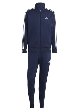 Tuta blu navy realizzato in tessuto morbido, composto da una giacca con zip e colletto alto, con strisce bianche lungo le maniche, e pantaloni a sigaretta coordinati.