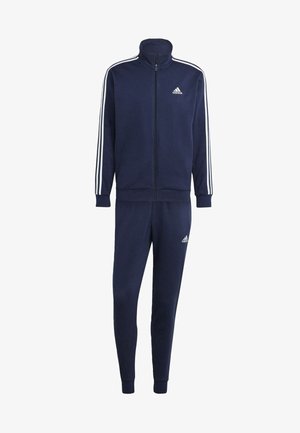 Tuta blu navy realizzato in tessuto morbido, composto da una giacca con zip e colletto alto, con strisce bianche lungo le maniche, e pantaloni a sigaretta coordinati.