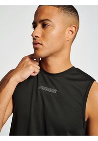 Zwarte mouwloze atletische shirt van een gestructureerde stof. Heeft een opvallend "HUMMEL" logo op de borst in contrasterende witte stiksels.