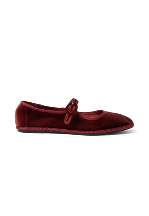 Scarpa Mary Jane piatta in velluto bordeaux con punta arrotondata, cinturino in tessuto e fibbia circolare su sfondo bianco.