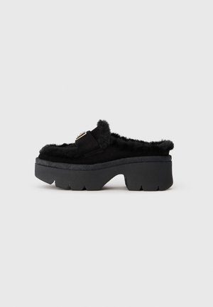 Mules à plateforme noires avec un doublure en fausse fourrure, tige en daim et un accent de boucle. Semelle en caoutchouc épaisse avec un motif de grip texturé.