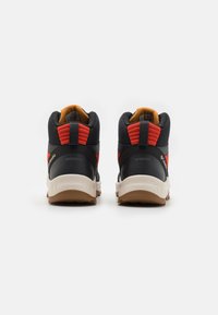 Schwarze und rote wasserdichte Wanderschuhe mit einem strukturierten Netz-Obermaterial, gepolstertem Schaft und kontrastierender Gummisohle. Subtile Markenkennzeichnung an der Seite.