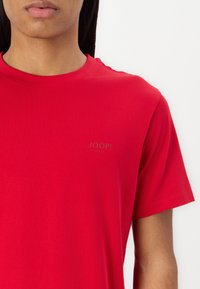 Camiseta de algodón roja con escote redondo y mangas cortas. Presenta un pequeño y sutil logo "JOOP!" en un tono más claro en el pecho.