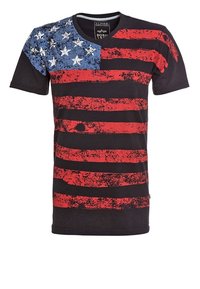 Svart t-shirt med röda ränder och ett blått stjärnmönster på vänster axel, med en sliten struktur och rundad halsringning.