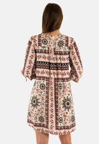 Vestido de estampado floral en rosa claro, con acentos en negro y rojo, mangas plisadas y un corte holgado con escote redondo.