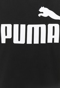 T-shirt noir avec le texte blanc audacieux "PUMA" et un logo panthère bondissante. Le matériau semble lisse, avec un design classique à col rond.