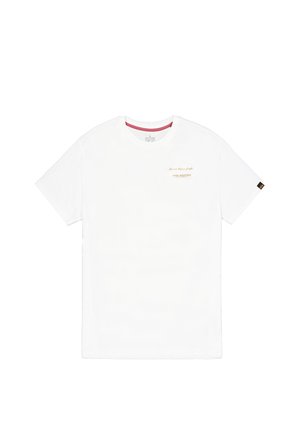 Maglietta bianca a maniche corte con scollo rotondo, con piccolo testo arancione "Alpha Industries" e slogan sul petto a sinistra, e una piccola etichetta nera sulla manica destra.