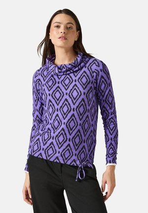 Top lungo viola a maniche lunghe con collo a scialle, motivo a diamante nero, tessuto testurizzato e orlo con cordoncino in vita. Abbinato a pantaloni neri.
