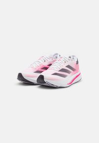 Un paio di scarpe da corsa Adidas bianche e rosa con strisce nere, lacci bianchi e suole imbottite su uno sfondo bianco.