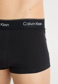 Zwarte katoenen boxershorts hebben een zachte tailleband met "Calvin Klein" geborduurd in het wit. Soepel, aansluitend ontwerp met een lage taille.
