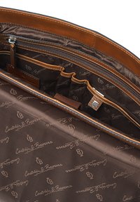 Interno di una borsa in pelle marrone con più scomparti, tasca con zip e rivestimento stampato ripetutamente con il logo "Castelijn & Beerens".