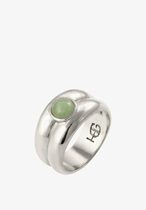 Silberner Ring mit glatten, abgerundeten Kanten und einem zentralen grünen Edelstein. Graviertes Logo innenseitig des Rings. Polierte Oberfläche und glänzende Textur.