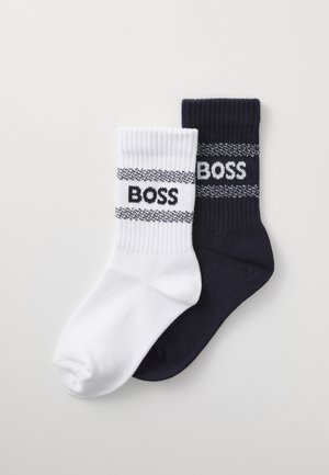 Calcetines de mezcla de algodón en blanco y azul marino, con puños acanalados y el logo "BOSS" en contraste con dos rayas horizontales. Textura suave.