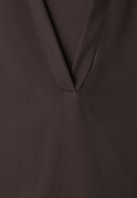 Dark brown fabric with a V-shaped neckline and visible stitching along the edges.