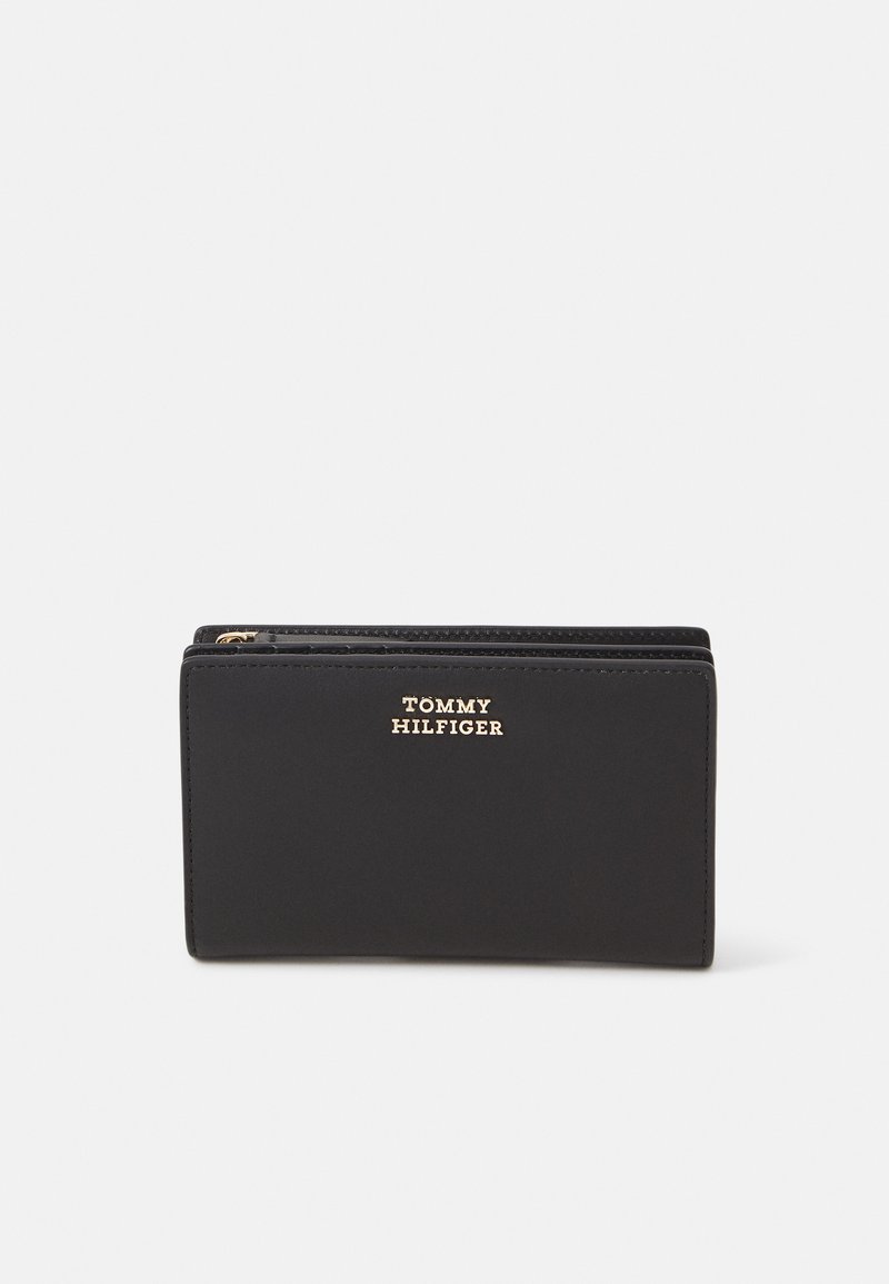 Black wallet made of smooth leather, featuring a gold logo on the front and a zip closure. Rectangular shape with clean lines.