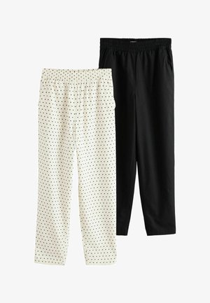 Deux pantalons à taille élastique, un noir uni et un blanc à pois noirs, présentés à plat sur un fond blanc.
