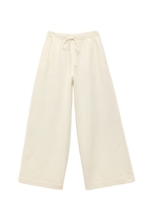 Pantalones amplios color crema con cinturilla elástica y cordón. Textura suave, hasta la rodilla, con un corte holgado y sin patrones visibles.