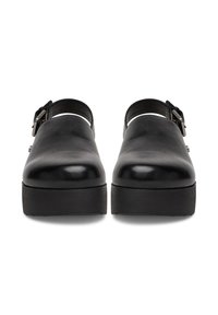 Clog-uri negre din piele cu un finisaj neted, având o cataramă frontală și o talpă groasă texturată. Vârf închis cu bretele ajustabile la toc.