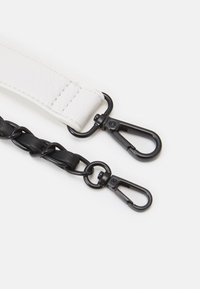 Sorte og hvide skulderrem med et glat hvidt læderafsnit og et tekstureret sort flettet design; metalclips i begge ender.