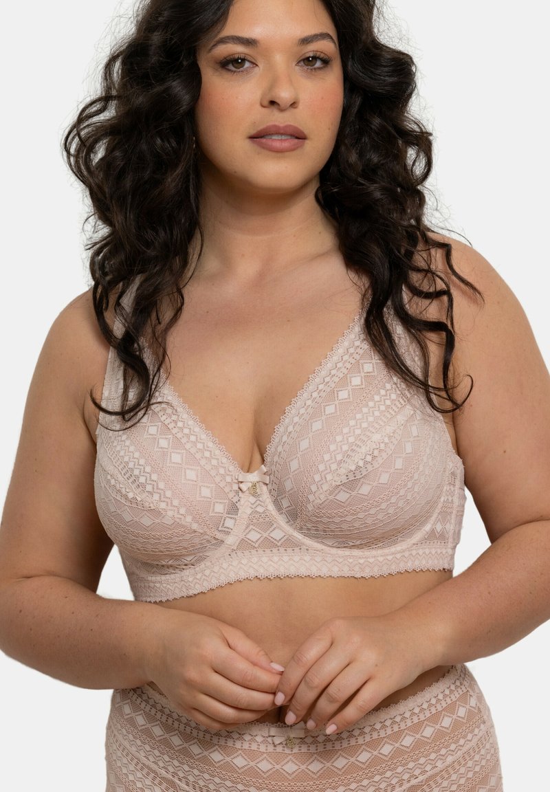 Bralette en dentelle rose avec des motifs géométriques, bonnets triangulaires, bretelles réglables et un nœud au centre. Fini doux et texturé.