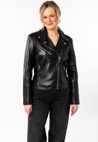 Giacca moto in pelle nera con zip asimmetrica, hardware argentato e due tasche con zip. Texture liscia con design aderente.
