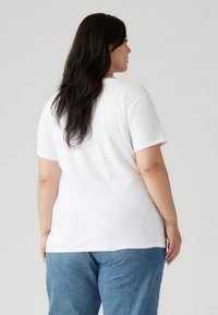 Hvit T-skjorte med korte ermer laget av myk bomull, med rund hals og løs passform. Kombinert med lyseblå baggy jeans.