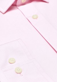 Jasnoróżowa koszula wizytowa o gładkiej fakturze, z pojedynczą kieszenią na piersi i żółtymi guzikami na przednim listwie.